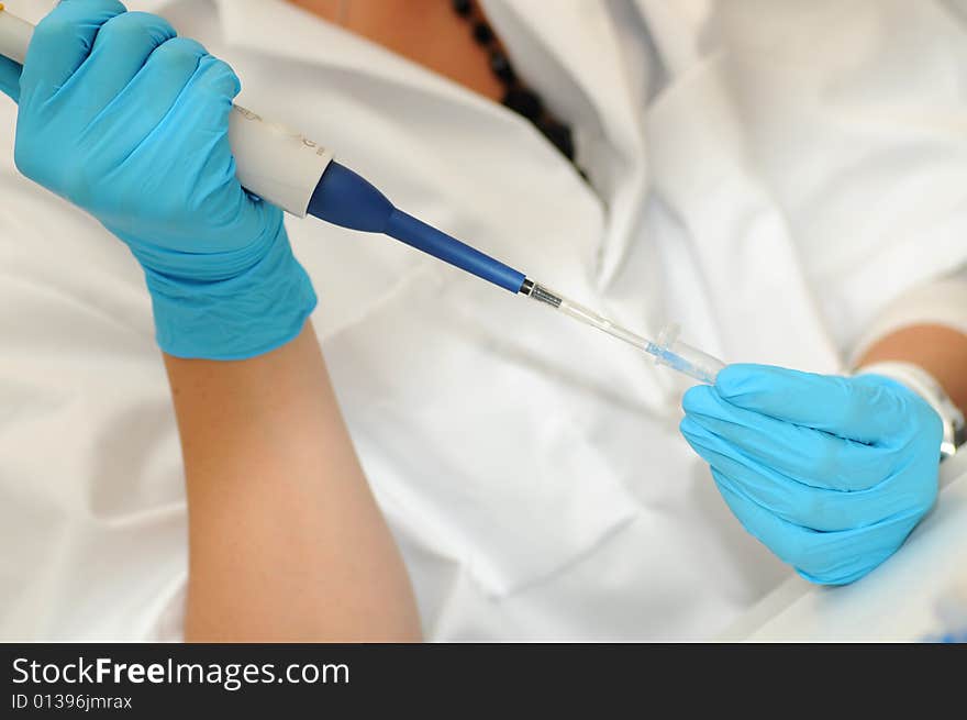 Researcher is pipetting, while protected with lab coat and gloves.