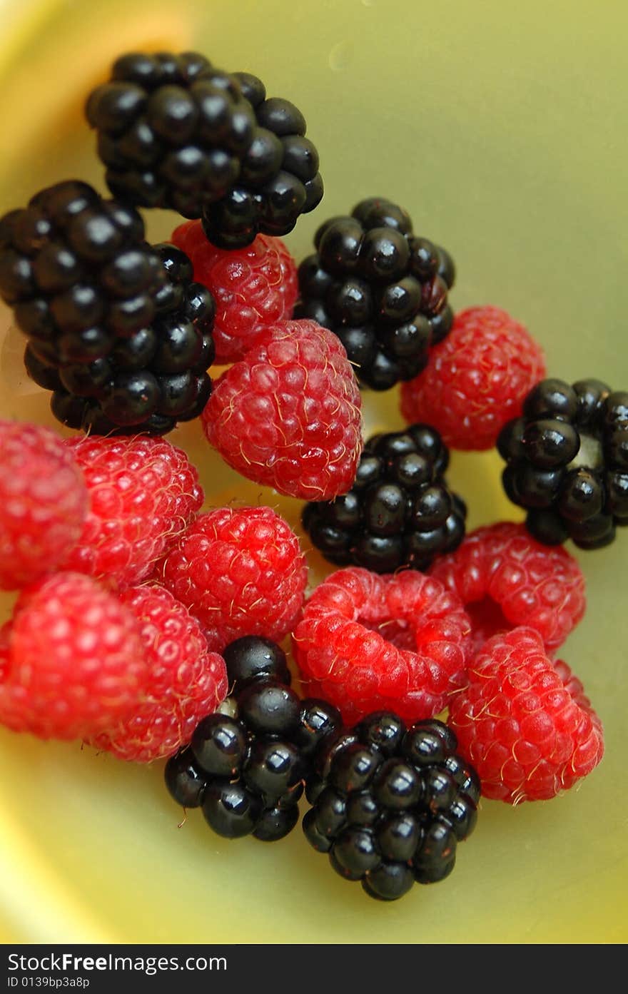 Blackberry and raspberry in a yellow bowl. Blackberry and raspberry in a yellow bowl