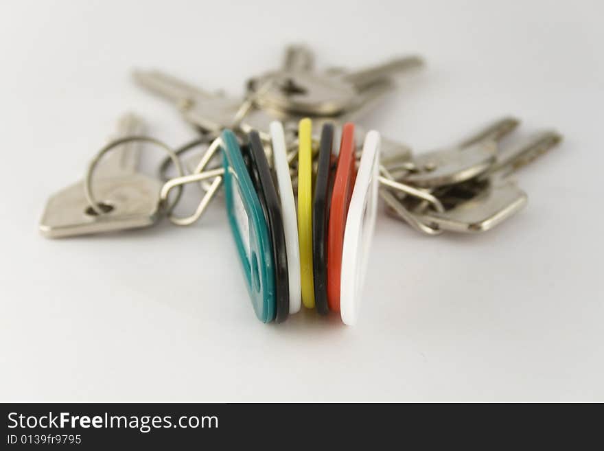 Vertically placed green, white, yellow, red and black key chains with text labels and keys. Focus is on the key fobs.