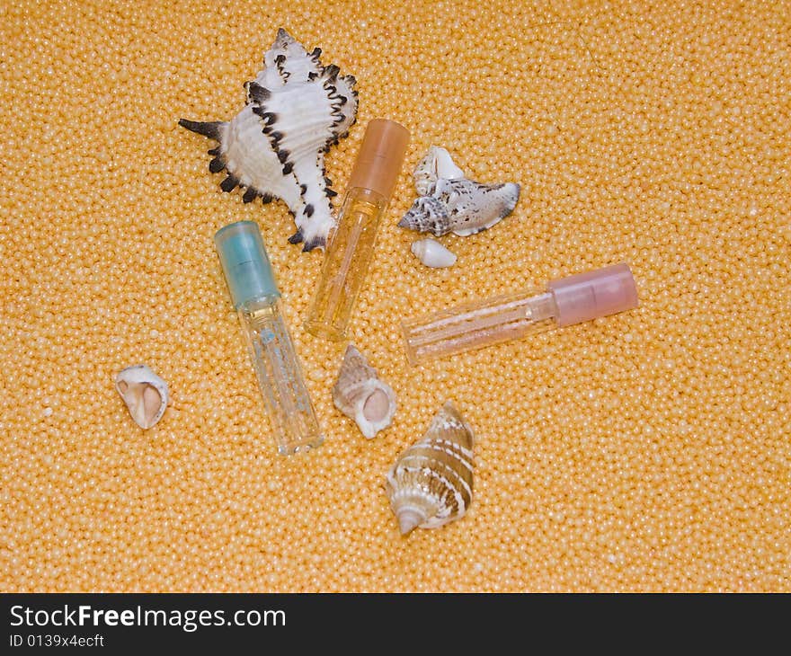 The image of bottles of perfume and cockleshells on a yellow background. The image of bottles of perfume and cockleshells on a yellow background