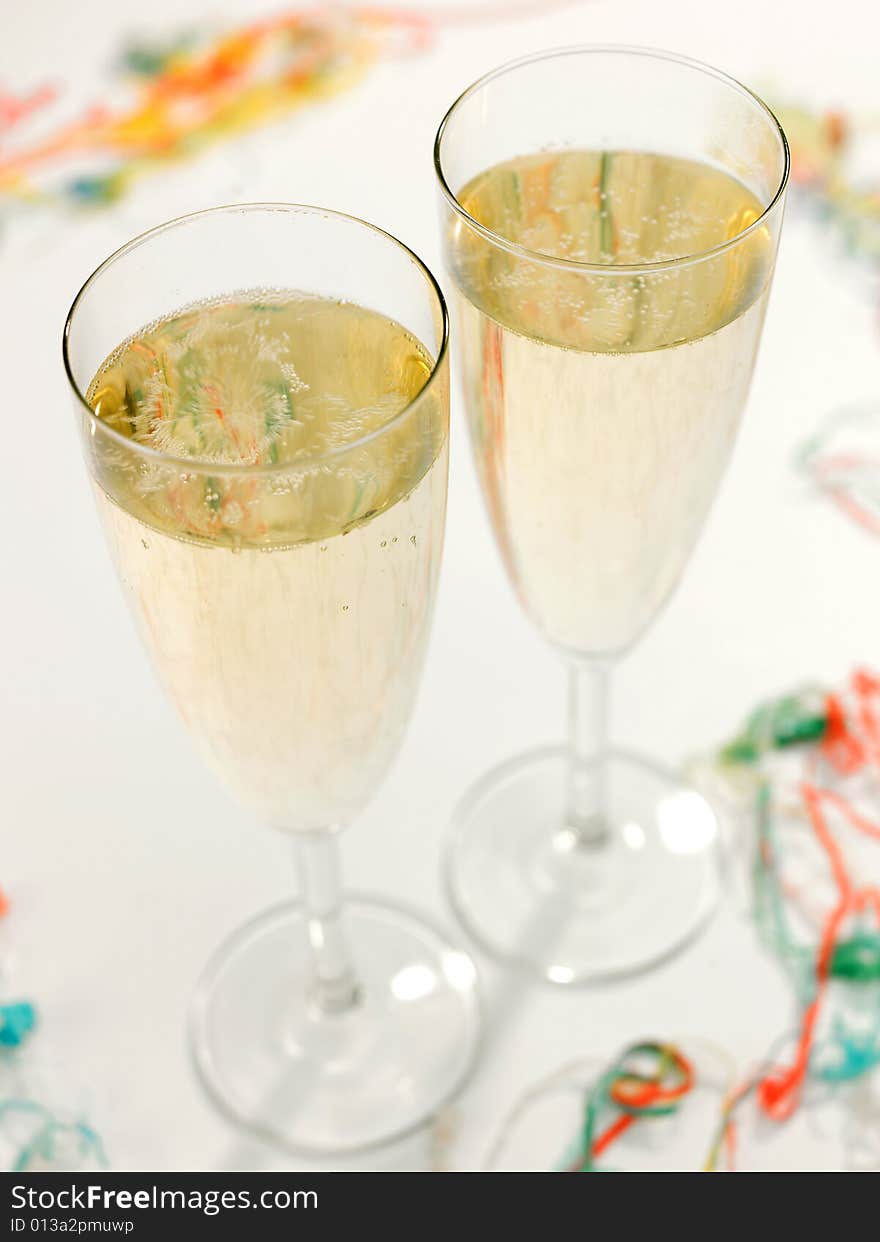 Two Champagne flute glasses with Champagne with party streamers at base. Two Champagne flute glasses with Champagne with party streamers at base