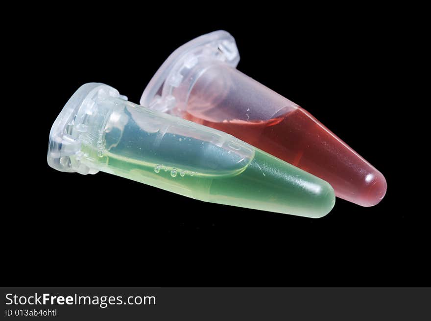 Eppendorf vials with red and green liquid isolated on black background