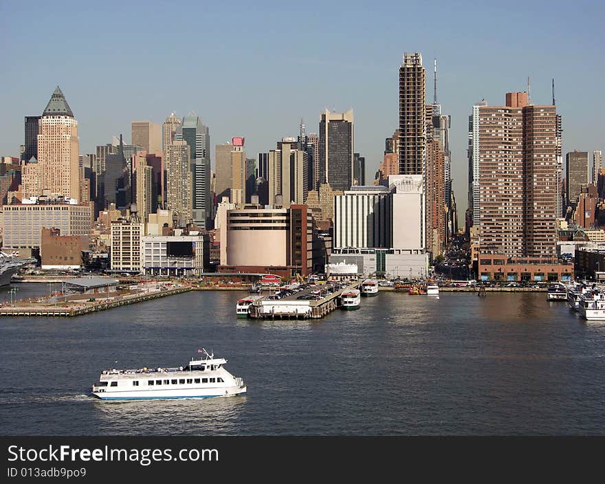 The evening view of the water transport boat passing by and Manhattan landmark with a straight street where you can see the other side of the island (New York City). The evening view of the water transport boat passing by and Manhattan landmark with a straight street where you can see the other side of the island (New York City).