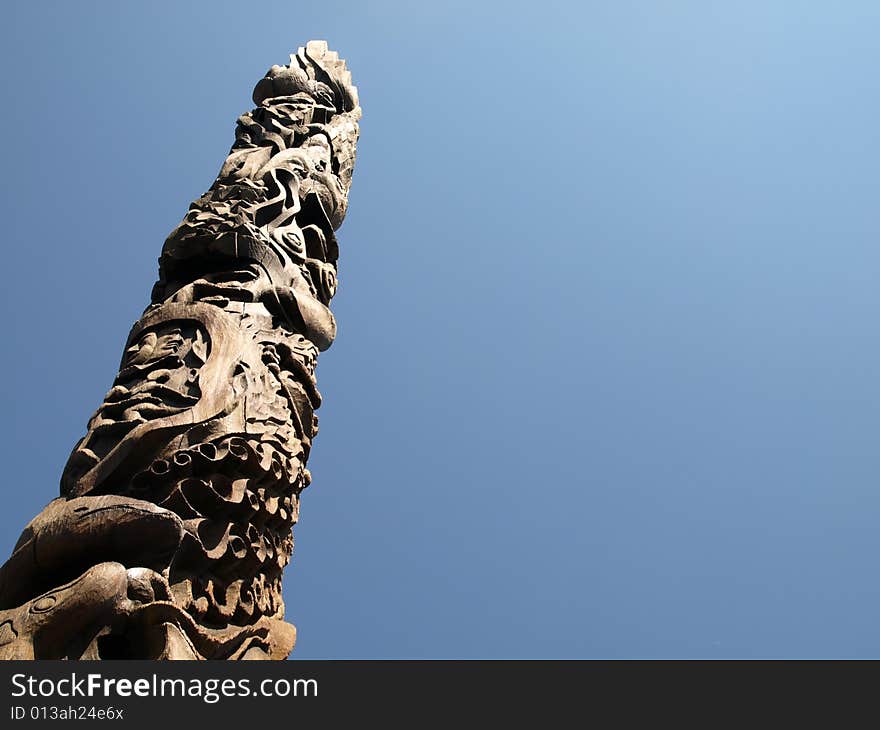 A carved wooden totem pole on a clear day.