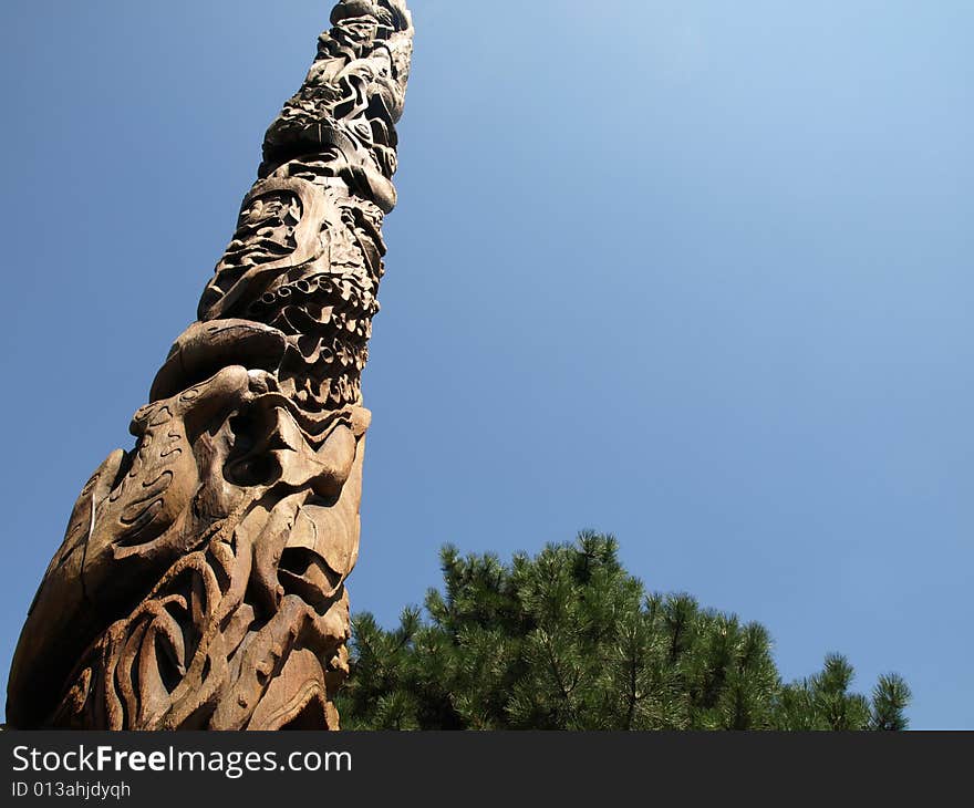 A Canadian Totem Pole with trees on a clear day.