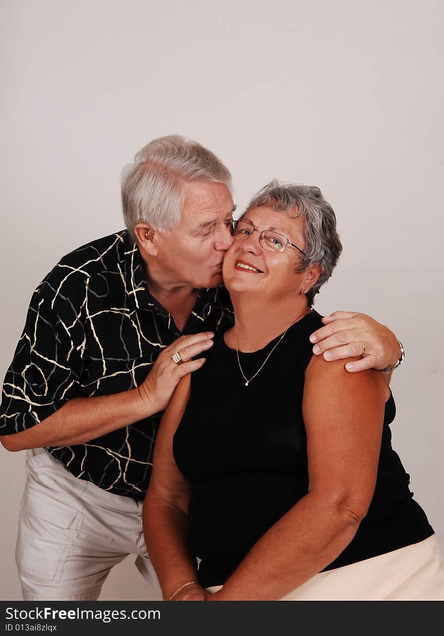 An happy senior couple kissing in front of the camera. An happy senior couple kissing in front of the camera.