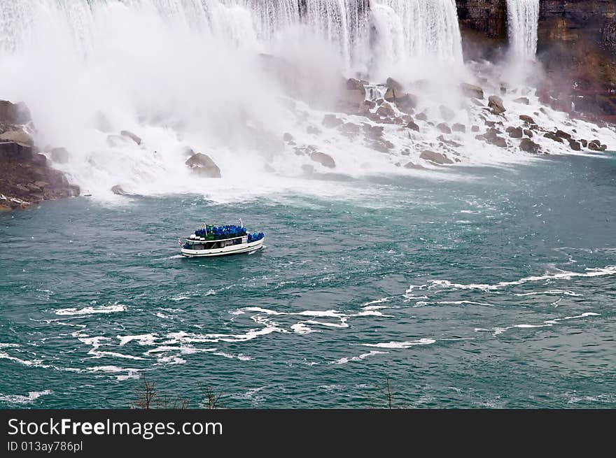 A boat sailing in a river next to Niagara falls. A boat sailing in a river next to Niagara falls