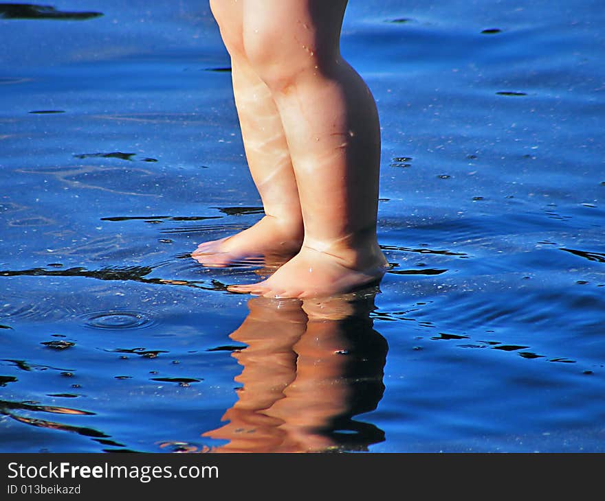 The legs of a child in the blue water. The legs of a child in the blue water.