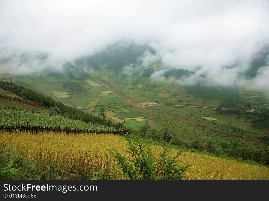 The photo is about Yunnan province of China, there is a large field in front of a mountain, there are some clouds in the sky. The photo is about Yunnan province of China, there is a large field in front of a mountain, there are some clouds in the sky.