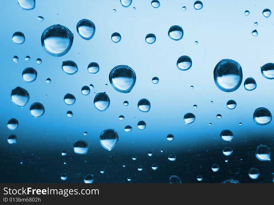 Blue water drops on the glass (abstract background)