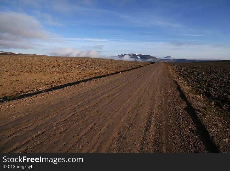 A dirt road running through a stone desert lit by the setting sun. A dirt road running through a stone desert lit by the setting sun.