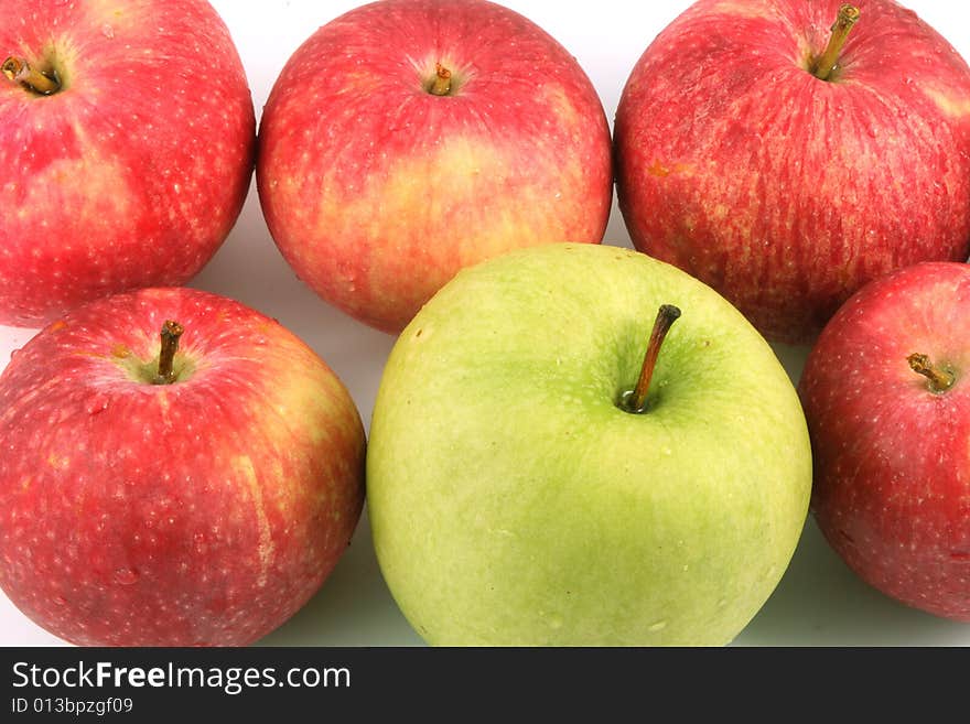 A lot of red and one green apple on a light background. A lot of red and one green apple on a light background