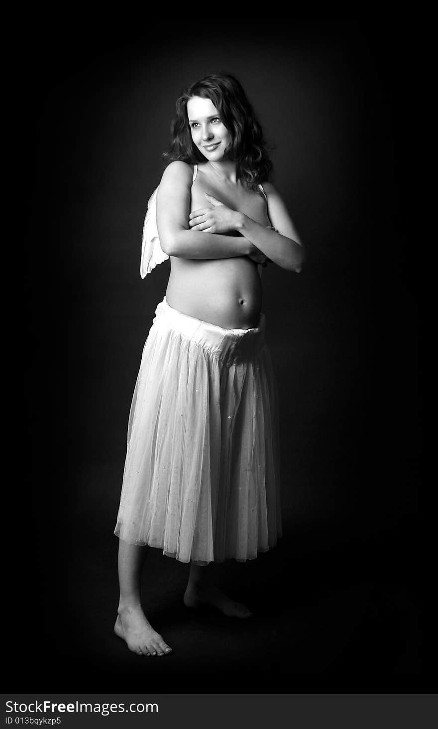 Pregnant woman on a black background with angel wings