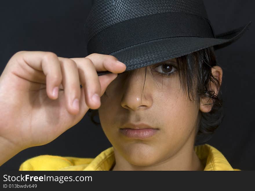 Teenager with black hat isolated on black background. Teenager with black hat isolated on black background