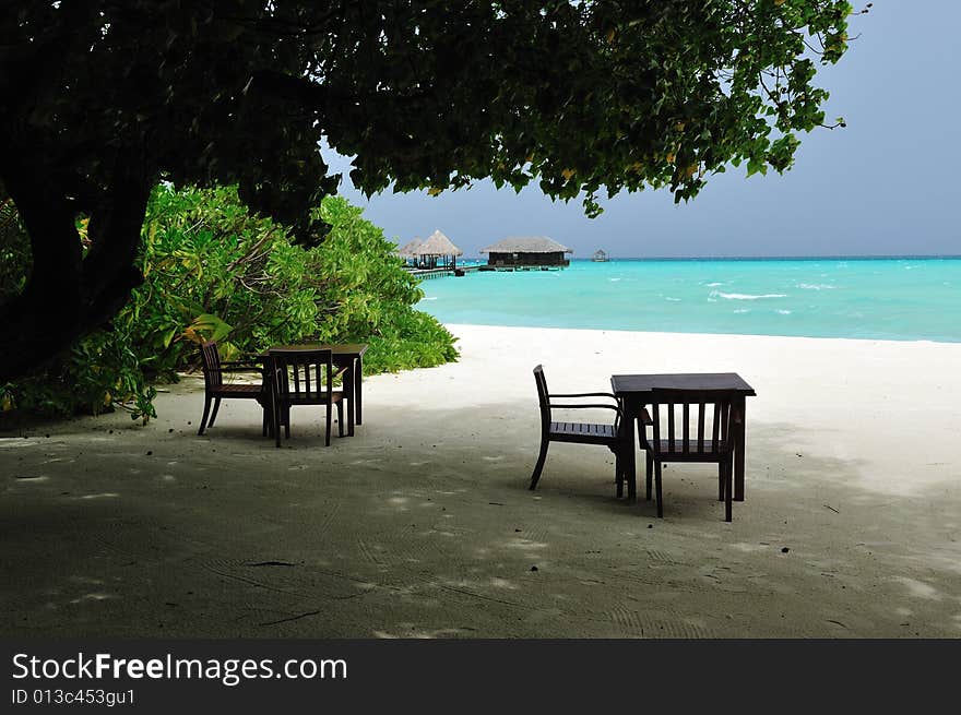 Couple of tables and chairs on a sandy beach in Maldives