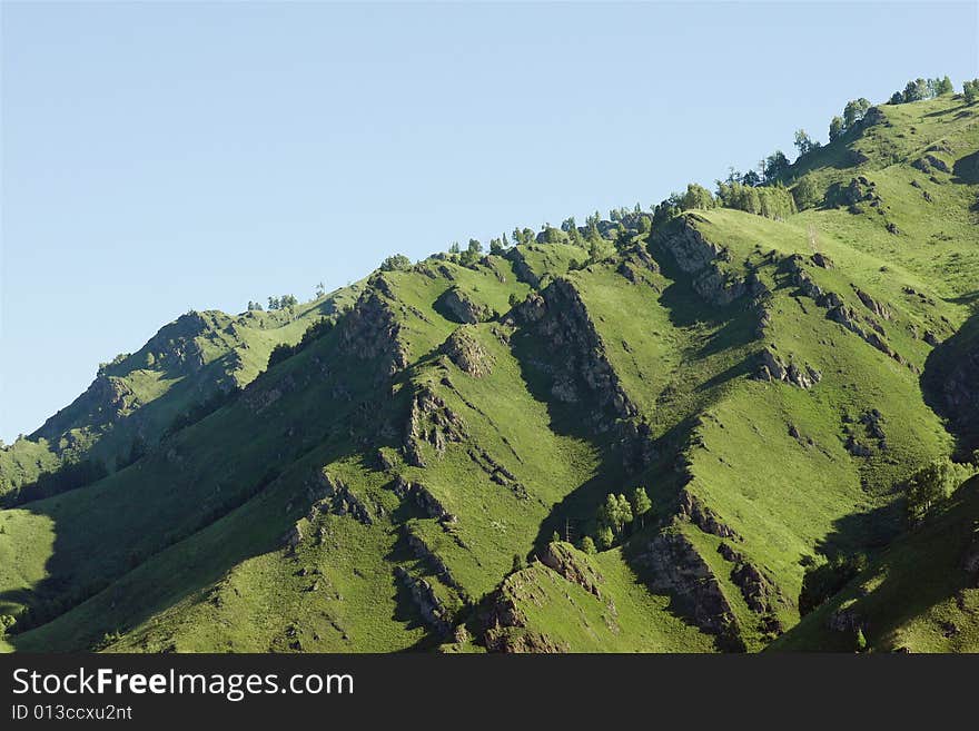 Mountains with green forest on blue sky. Mountains with green forest on blue sky