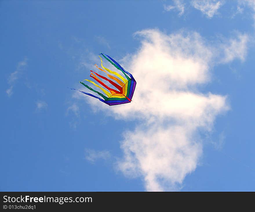 The rainbow kite flies in the blue sky