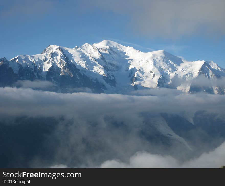 Mont Blanc in the sun, lower part below fog. Highest peak of the Alps. Hight 15775 ft. - 4808 m (15722 ft. - 4792 m without the ice). Mont Blanc in the sun, lower part below fog. Highest peak of the Alps. Hight 15775 ft. - 4808 m (15722 ft. - 4792 m without the ice).