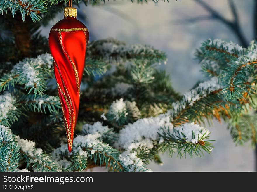 Twisty red icicle bauble on tree with snow