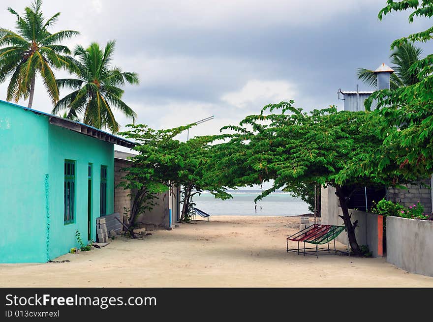 A narrow sandy street on an inhabited island in the Maldives