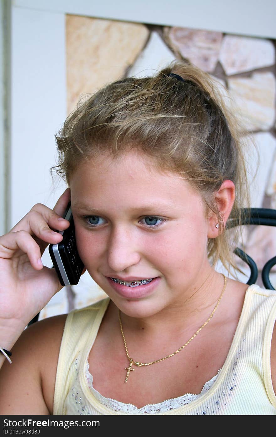 Photo of a 12 year old beautiful girl talking on her cell phone to her friends. Photo of a 12 year old beautiful girl talking on her cell phone to her friends