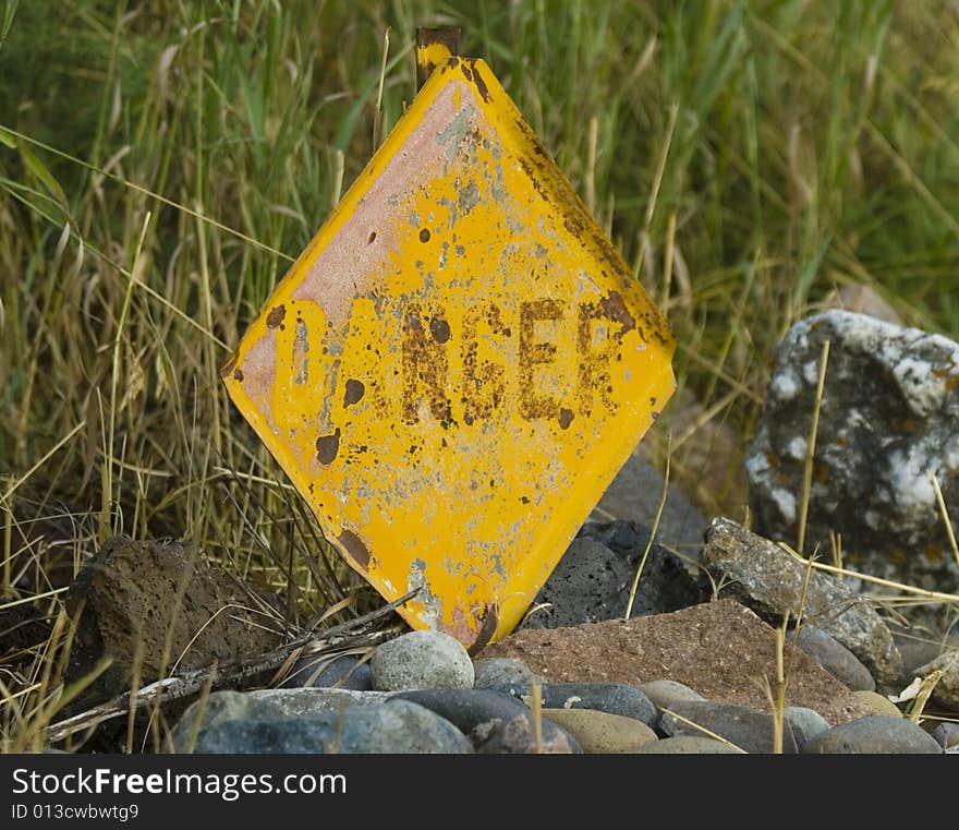 Rusty danger sign with missing letters.