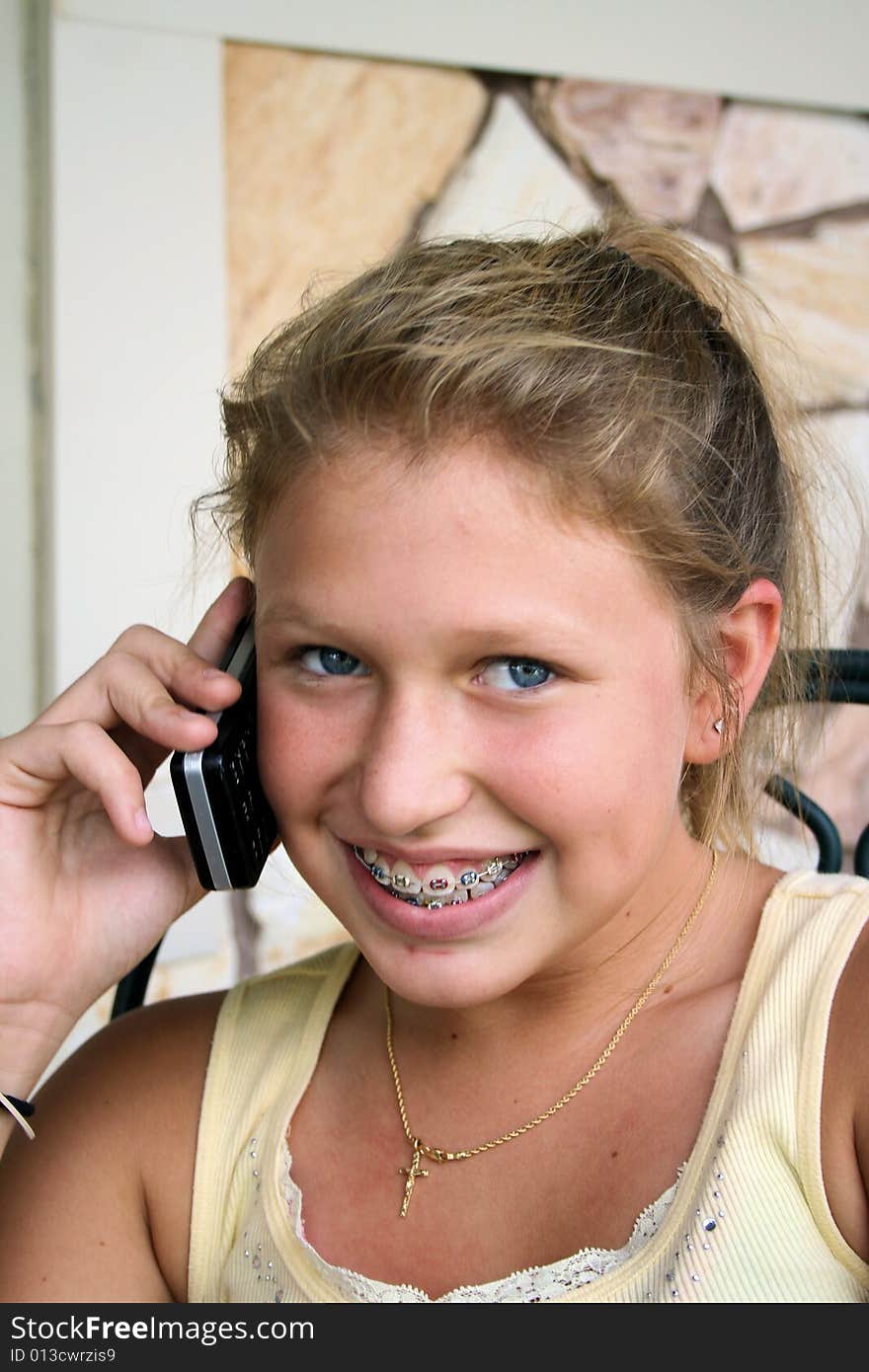 Photo of a 12 year old beautiful girl talking on her cell phone to her friends. Photo of a 12 year old beautiful girl talking on her cell phone to her friends