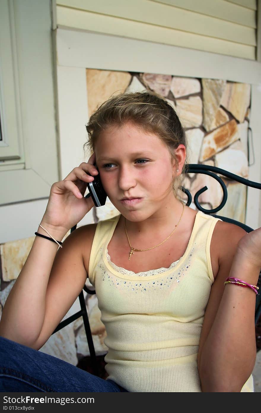 Photo of a 12 year old beautiful girl talking on her cell phone to her friends. Photo of a 12 year old beautiful girl talking on her cell phone to her friends