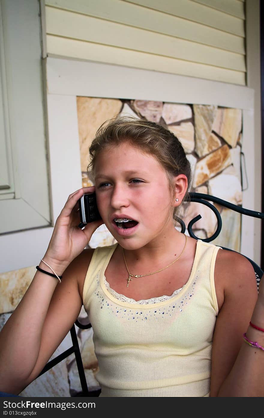 Photo of a 12 year old beautiful girl talking on her cell phone to her friends. Photo of a 12 year old beautiful girl talking on her cell phone to her friends