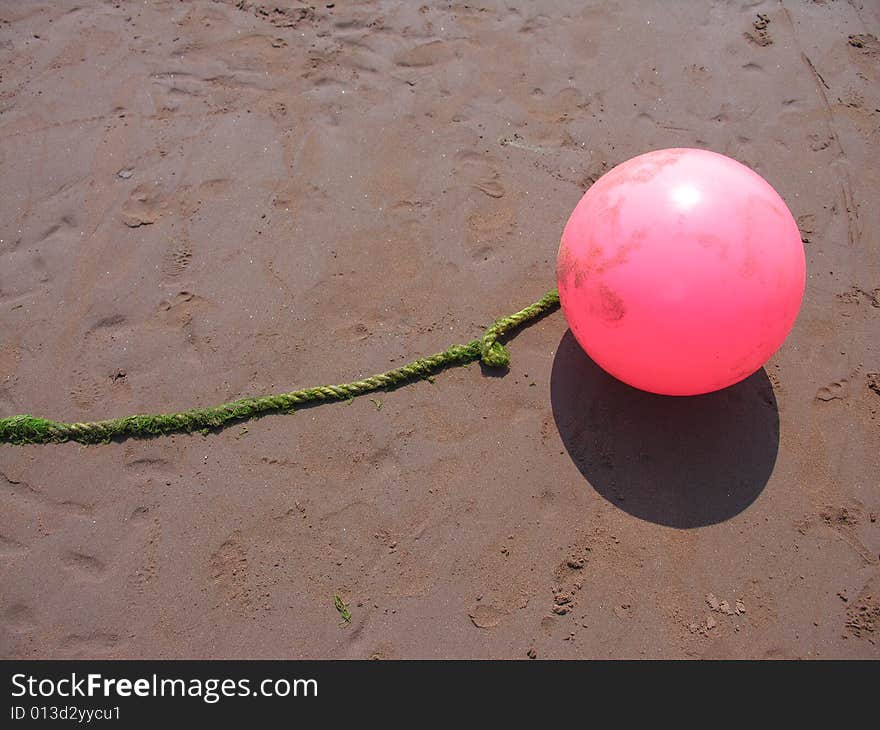 Pink buoy on sand