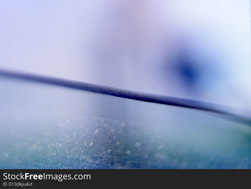 Blue and aqua abstract textured background with horizontal slightly diagonal line with glass texture in bottom half and blue spot in top half. Blue and aqua abstract textured background with horizontal slightly diagonal line with glass texture in bottom half and blue spot in top half