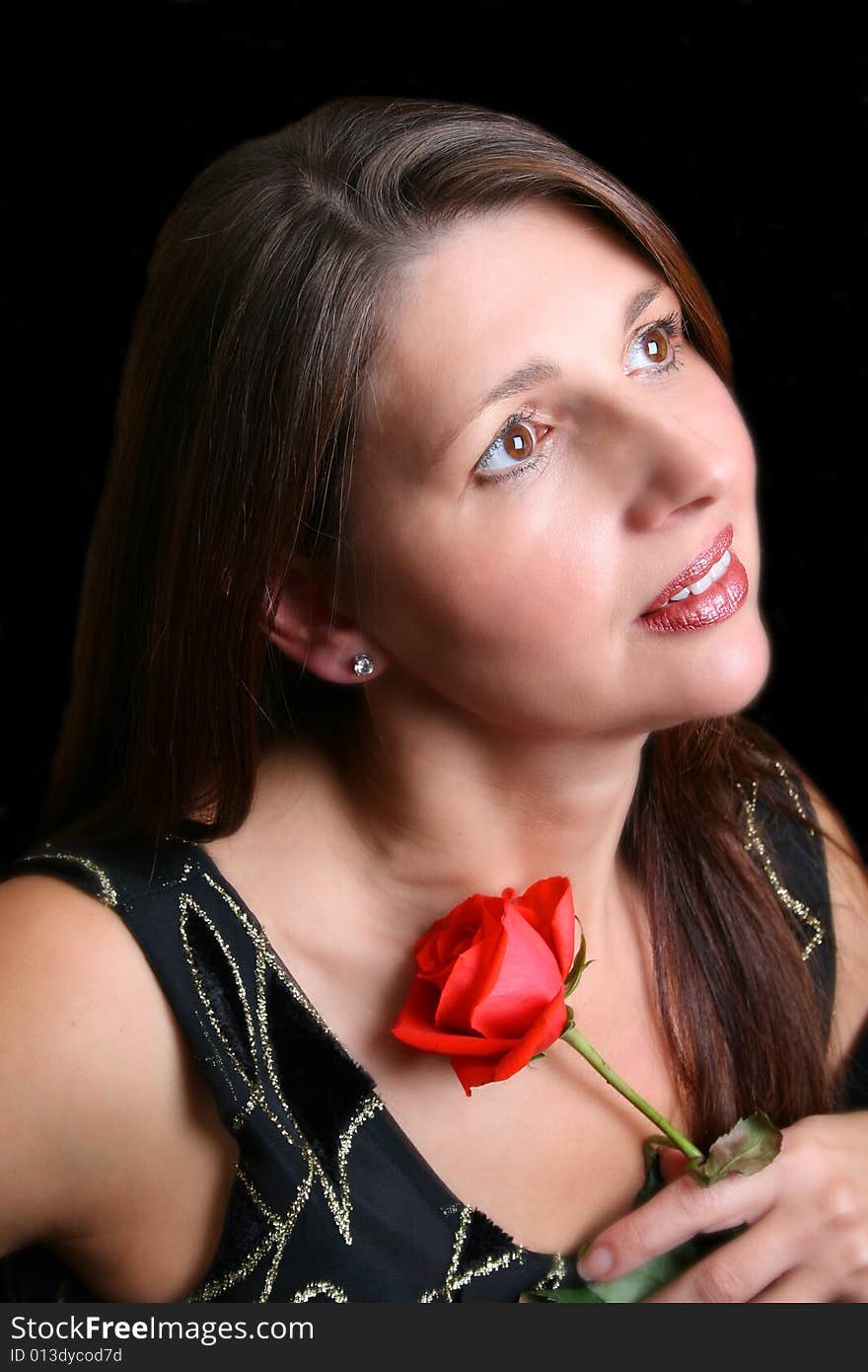 Brunette model holding a red rose, looking into the distance