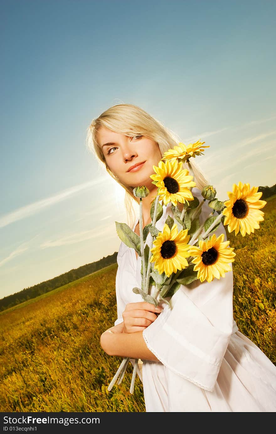 Young beautiful woman with a bouquet of sunflowers in the field. Young beautiful woman with a bouquet of sunflowers in the field