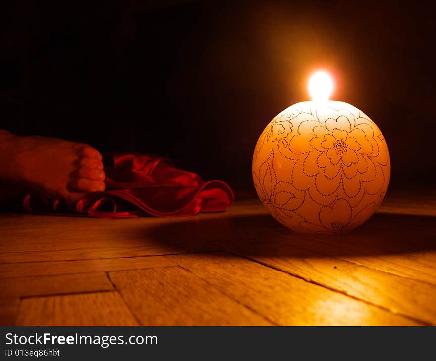 Light round candle near women foot and red cloth on the floor. Light round candle near women foot and red cloth on the floor