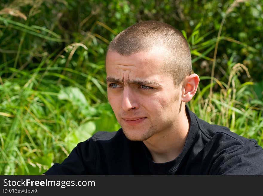 Man sitting on the background of green grass portrait