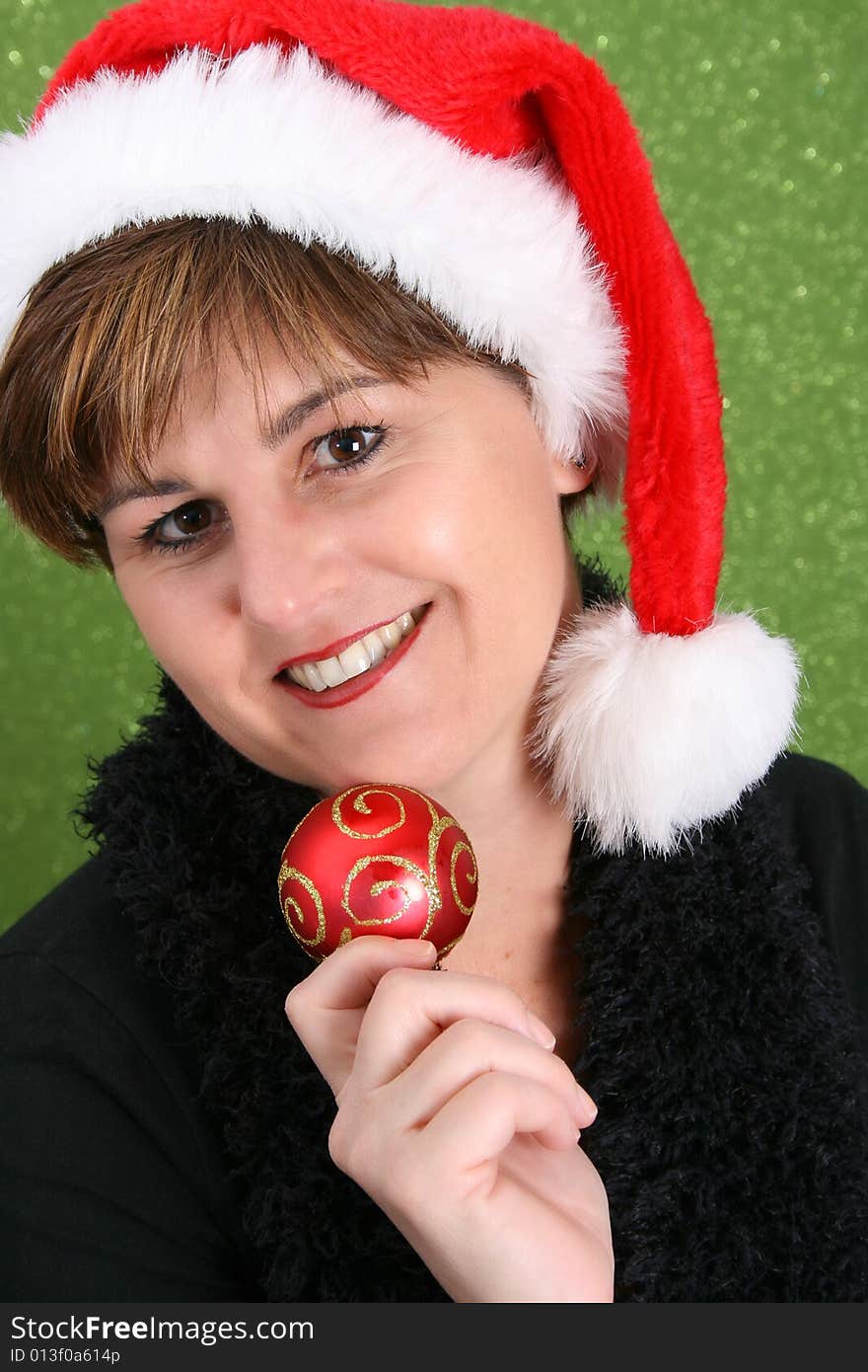 Adult female wearing a christmas hat, holding a decoration. Adult female wearing a christmas hat, holding a decoration