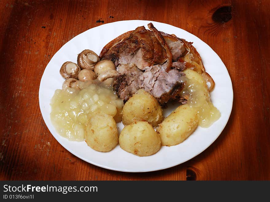 Roast pork, potatoes,and mushrooms on a rustic kitchen table. Roast pork, potatoes,and mushrooms on a rustic kitchen table