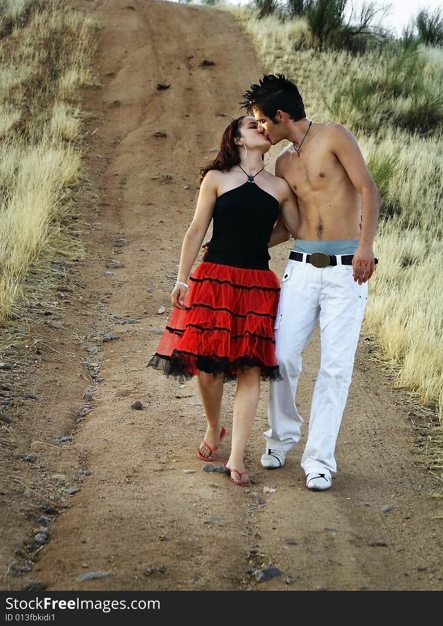 A boy and a girl kissing on a country road. A boy and a girl kissing on a country road.