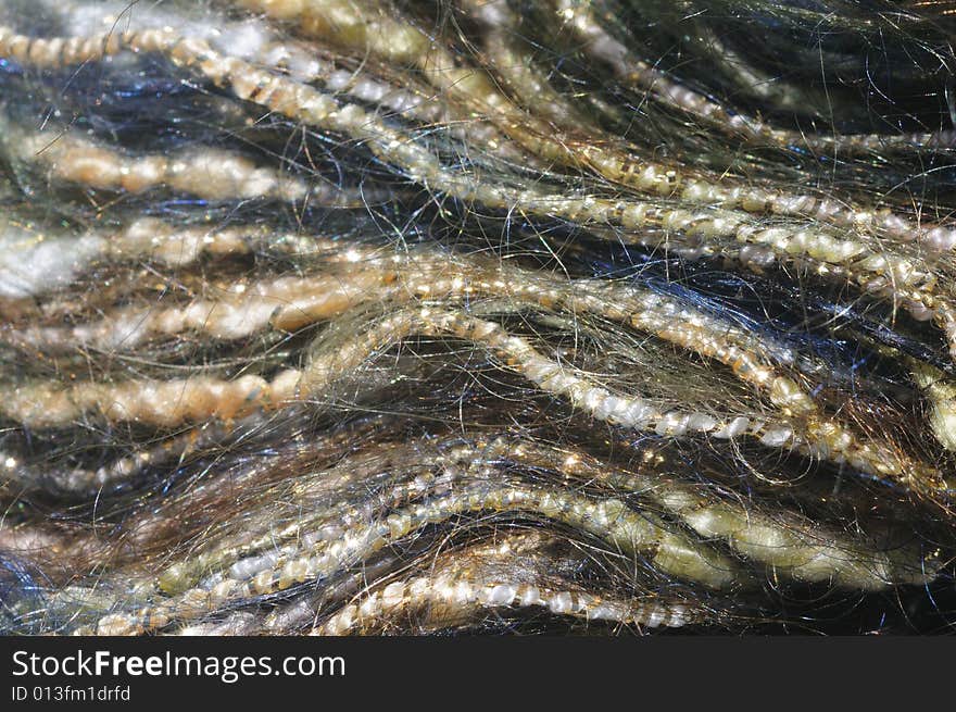 Close-up (macro) of blue and yellow mohair yarn wrapped in gold strands, forming wavy lines. Close-up (macro) of blue and yellow mohair yarn wrapped in gold strands, forming wavy lines