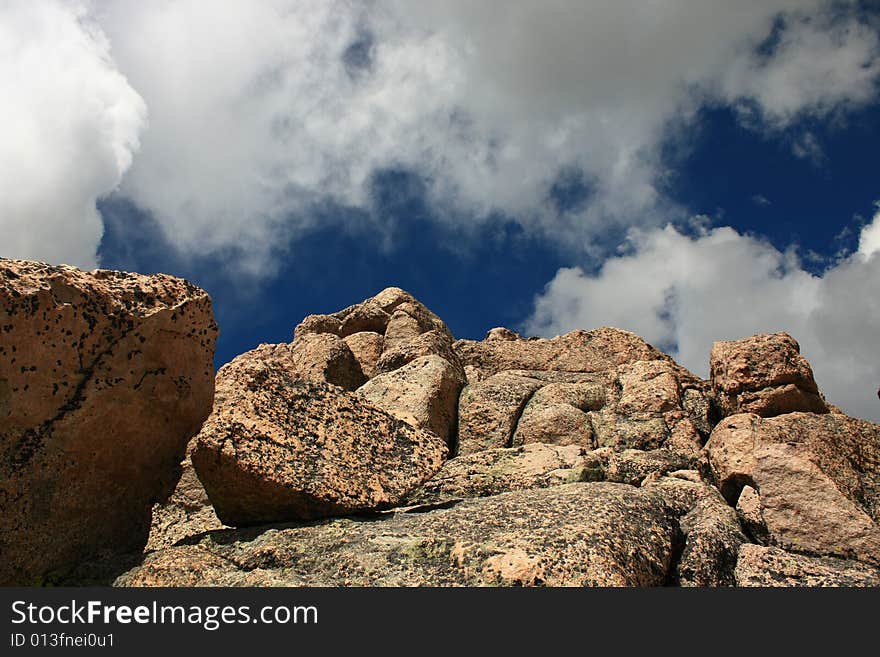 View of pinkish granite rock formation looking upwards against blue sky and white clouds