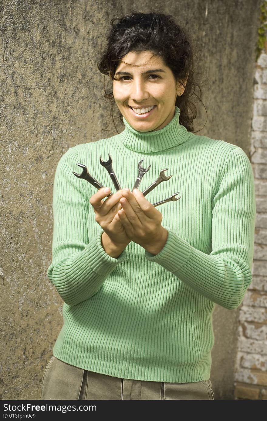 Woman holds wrenches in front of camera. She is smiling. Vertically framed photo. Woman holds wrenches in front of camera. She is smiling. Vertically framed photo.