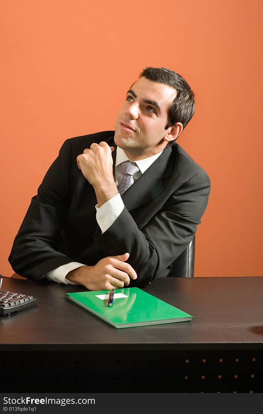 Businessman seated at desk looking at paperwork. Vertically framed photo. Businessman seated at desk looking at paperwork. Vertically framed photo.