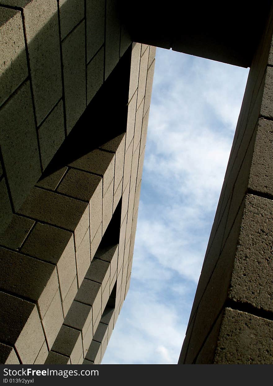 View from below a building with the sky peeking through. Vertically framed photo. View from below a building with the sky peeking through. Vertically framed photo.