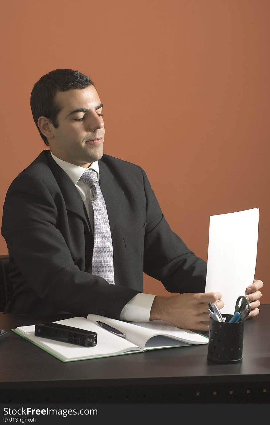 Businessman looking at paperwork at his desk. Vertically framed photograph. Businessman looking at paperwork at his desk. Vertically framed photograph.