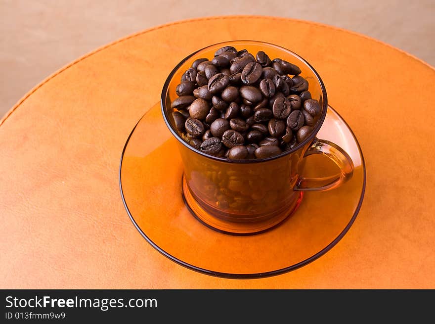 A cup with coffee beans on a table. A cup with coffee beans on a table