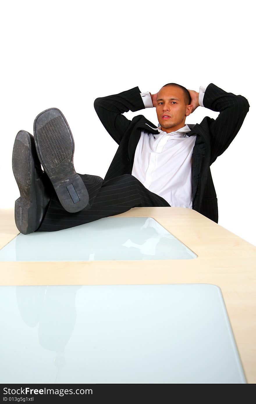 A young satisfied businessman sitting by desk at office feet on table thinking. A young satisfied businessman sitting by desk at office feet on table thinking.