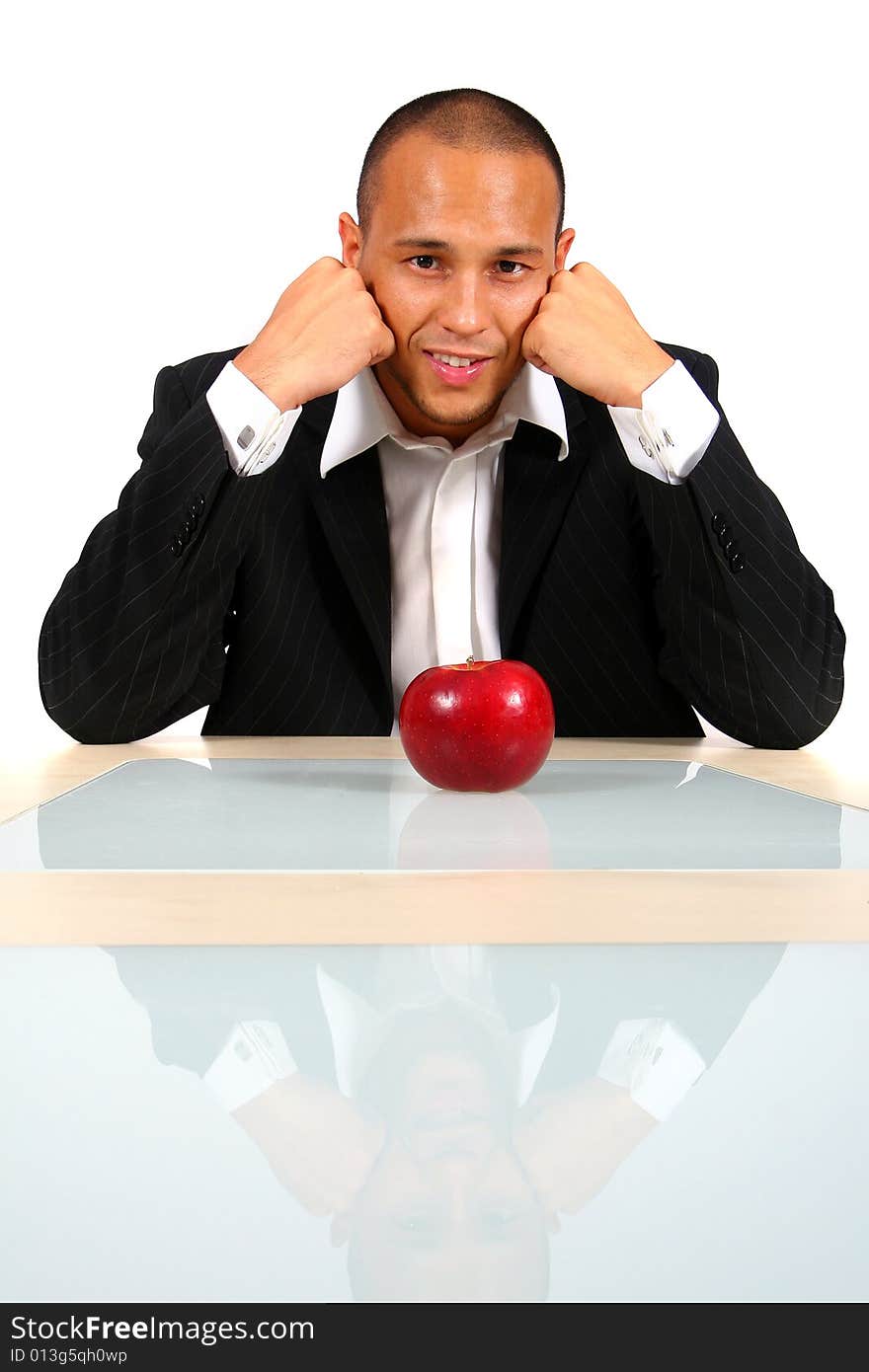 Young businessman sitting in front of a red apple thinking and smiling. Isolate over white. Young businessman sitting in front of a red apple thinking and smiling. Isolate over white.