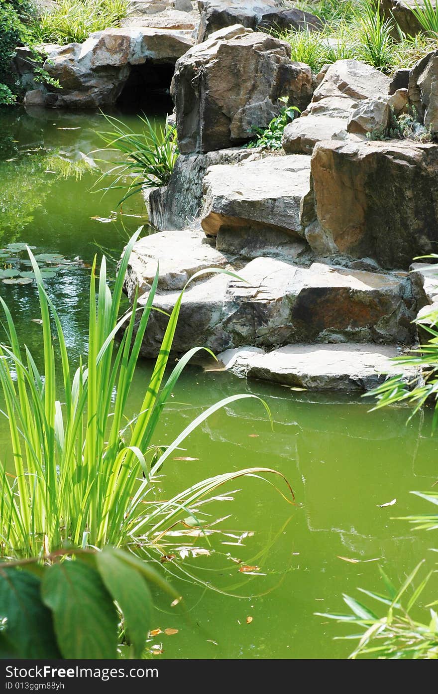 Rocks and green plants and stream flowing into lake. Rocks and green plants and stream flowing into lake