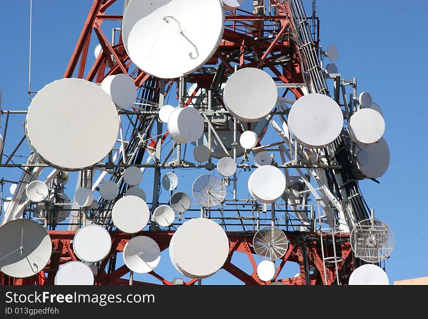 Lots of satellite dishes on a big antenna. Lots of satellite dishes on a big antenna