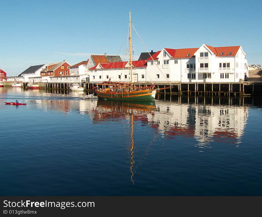 Old sailor mirroring in Henningsvaer's main channel, Lofoten islands, Norvegian arctic sea. Old sailor mirroring in Henningsvaer's main channel, Lofoten islands, Norvegian arctic sea